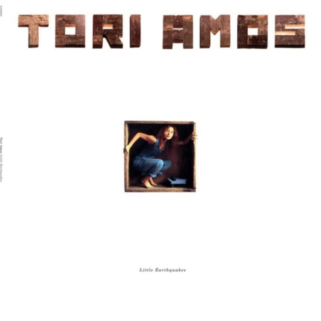 Tori Amos - Little Earthquakes (vinyl) album cover featuring the artist crouched inside a small wooden box wearing blue jeans and a sleeveless top, with 'TORI AMOS' spelled out in large wooden block letters above and the album title in small text below on a white background, ideal for collectors of classic pop vinyl records.