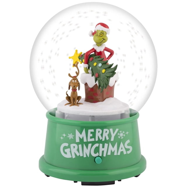 Snow Globe-4.5-inch Grinch Scene by Dr. Seuss featuring the Grinch in a Santa outfit holding a decorated Christmas tree, with Max the dog sitting nearby on a snowy chimney base. The green base displays the text 'Merry Grinchmas' in white with snowflake accents. Ideal for indoor Christmas decorations and holiday celebrations.