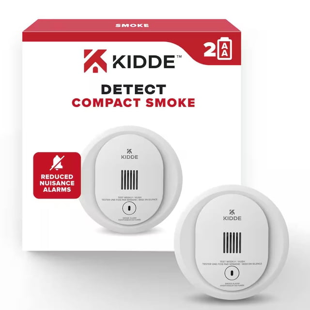 Kidde Smoke Alarm Compact Design, white round smoke detector with vented sensor and test button, powered by 2 AA batteries, designed to reduce nuisance alarms, shown with its branded packaging highlighting compact size and safety features for home use.