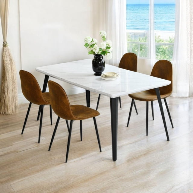 Homy Casa 63 inch Dining Set for 4 with a rectangular faux marble tabletop featuring seamless edges and black flat iron legs with adjustable foot pads. Includes four brown suede upholstered chairs with curved backs and black metal legs. Set in a bright room with light wood flooring and ocean view through sheer curtains. The table holds a black vase with white flowers and stacked plates. Often used in kitchens or apartments for modern ergonomic dining.