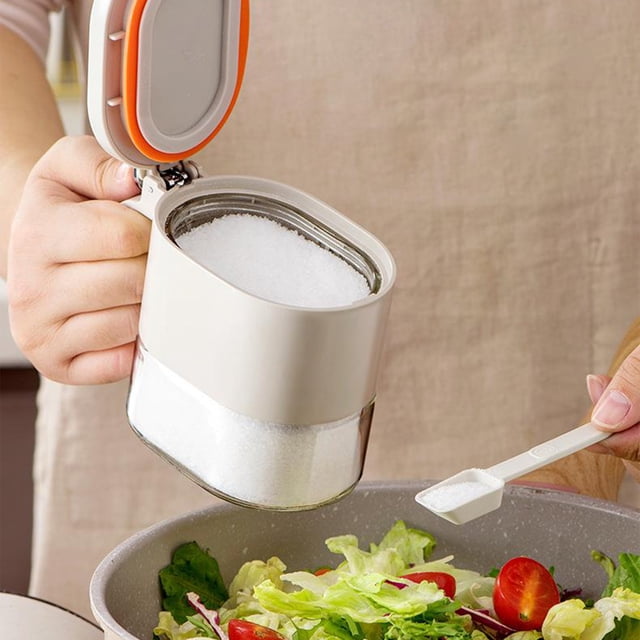TopLLC Glass Spice Jar, 380ml mini seasoning storage jar with flapper cap, ideal for kitchen organization and food storage. The jar is shown dispensing salt onto a salad, featuring a white lid with an orange sealing strip and a transparent glass base for keeping spices dry and easy one-hand operation.