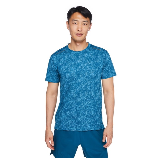 Athletic Works Men's Cut and Sew Tee in blue with breathable pointelle mesh fabric and DRI-MORE moisture-wicking technology, featuring a crew neckline, short sleeves, subtle all-over print, and high-low hem, shown front-facing with blue athletic shorts on white background.
