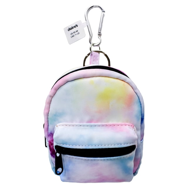 Claire's Girls Rainbow Tie Dye Mini Backpack Keychain made of white PU material with a vibrant rainbow tie dye design. Measuring 3.5” wide by 5” high by 1.5” deep, it features two black zippers for secure storage. The larger pocket fits lip balms, makeup, or earphones, while the front pocket is perfect for coins or small accessories. Includes a silver-tone carabiner for easy attachment to keyrings, purses, or backpacks.