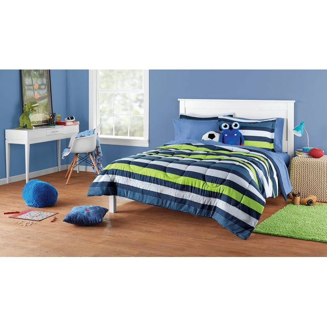 Stripe Bedding Set for Kids on a twin bed with a reversible comforter featuring bright blue, green, and navy stripes, solid blue sheets, and two striped pillow shams in a child's bedroom with blue walls, wooden floor, white desk, and playful decor including a stuffed monster and soccer ball, ideal for creating a cozy and versatile kids' room.