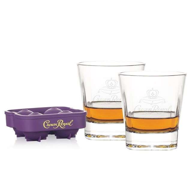 Crown Royal Ice Mold with 2 Premium Whisky Glasses featuring two clear 10 oz whiskey glasses with laser-etched Crown Royal logos, partially filled with amber whiskey, alongside a purple silicone ice mold that creates four large round ice spheres embossed with the Crown Royal logo, suitable for chilling whiskey without dilution.