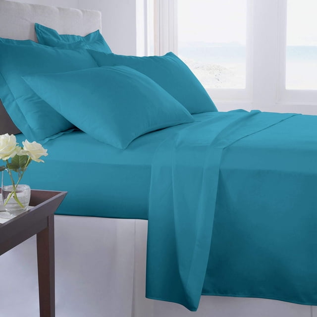 Johnson Home 500 Thread Count Certified Organic Cotton Sheet Sets in blue, displayed on a bed with smooth, breathable fabric and matching pillowcases, in a bright room with natural light and a bedside table with white flowers, suitable for year-round comfort and sensitive skin.