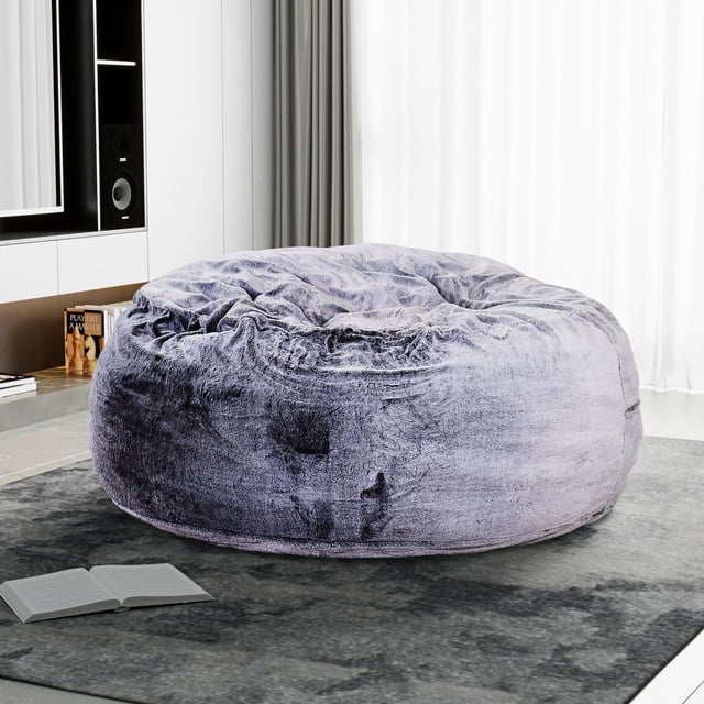 Sealy® Bala 5ft Faux Fur Memory Foam Bean Bag in taupe with plush faux fur upholstery and shredded foam filling, placed on a grey rug in a modern room with white curtains and shelving, suitable for kids' seating or lounging.