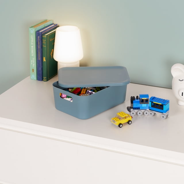 Neatfreak Boîte de Rangement pour Enfants avec Couvercle, Bleu Mat, Plastique Léger, avec Couvercle Partiellement Ouvert Montrant de Petits Jouets Colorés à l'Intérieur, Placée sur une Commode Blanche à Côté d'Une Lampe Blanche, de Livres et de Véhicules Jouets, Convient pour Organiser de Petits Articles et Maximiser l'Espace de Rangement.