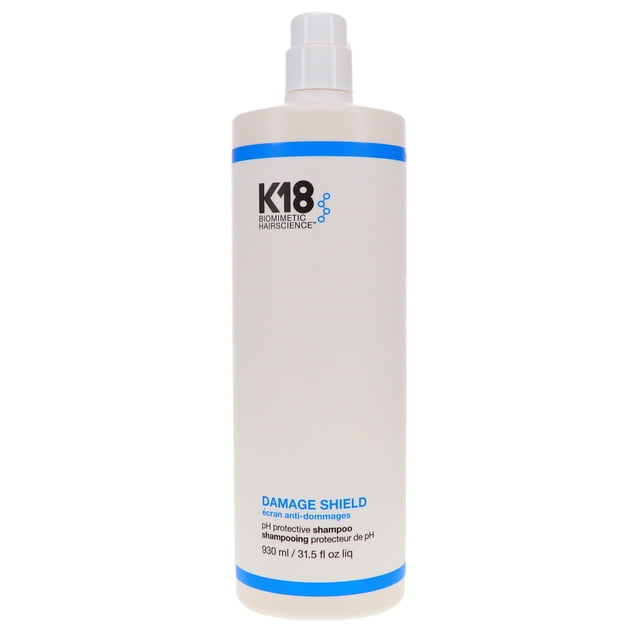 K18 DAMAGE SHIELD pH Protective Shampoo 31.5 oz bottle with a white body and blue accents, designed for repairing damaged hair and maintaining scalp health. Features a pH-balanced formula and K18PEPTIDE™ technology to restore hair bonds. Ideal for colour-treated and chemically damaged hair.