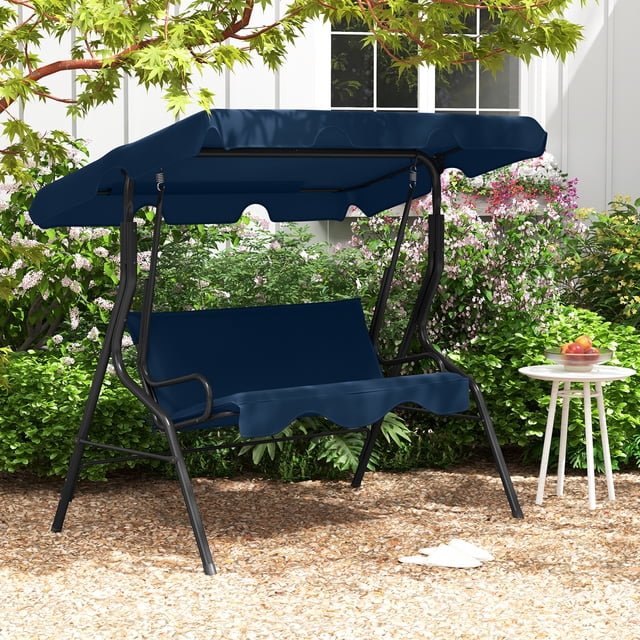 Costway Patio 3 Seats Canopy Swing Glider Hammock with a navy cushioned seat and adjustable canopy. This outdoor swing features a sturdy steel frame, curved armrests, and a wide seat accommodating up to three people. Ideal for porch seating or backyard relaxation, it is shown in a garden setting with greenery and a small side table nearby.