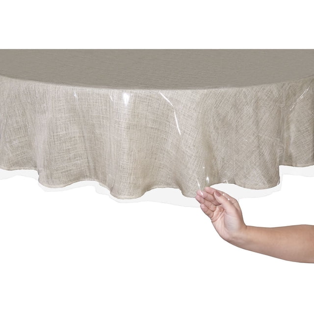 Mainstays Heavy Duty Tablecloth Protector, waterproof clear plastic cover on a beige textured round tablecloth, shown with a hand lifting the edge to highlight its flexible, easy-to-clean surface, ideal for protecting dining tables from spills and stains, also suitable for craft or work tables needing surface protection.