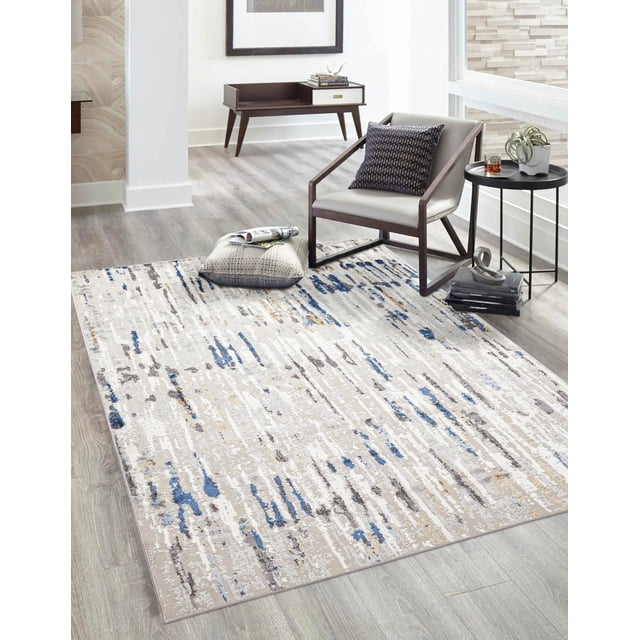 ECARPET Efes Contemporary/Modern Area Rug in grey with abstract distressed pattern featuring blue, beige, and taupe accents, placed on light wood flooring in a modern living room with a grey armchair, side table with plant and drink, and decorative cushions, ideal for living rooms, bedrooms, or entryways.