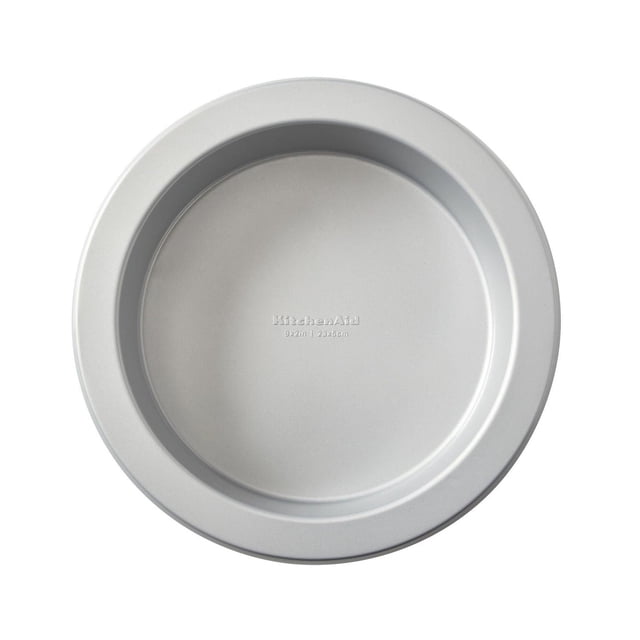 KitchenAid 9" Round Cake Pan made of heavy-duty aluminized steel with Whitford nonstick coating, shown from above with a smooth silver finish and embossed KitchenAid logo and size, designed for even heat distribution and easy cake release, also suitable for baking other round desserts.