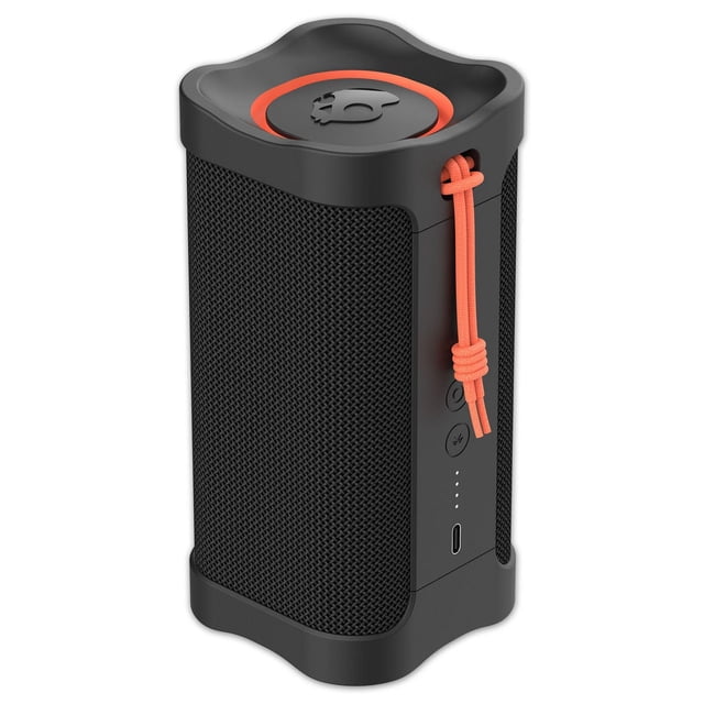 Skullcandy Terrain XT Compact Tough Wireless Speaker in black with orange accents, shown in a 3/4 front view. It features a textured mesh grille, rubberized frame with curved edges, orange cord loop, control buttons, LED battery indicators, and USB-C charging port. IPX7 waterproof with Bluetooth 5.1, it links up to 99 speakers wirelessly for outdoor use and is often used for portable group audio setups.