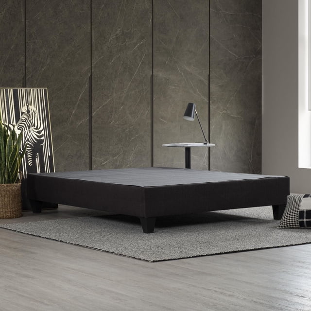 Carter Cadre de Lit Plateforme Rembourré Gris Foncé, Très Grand, avec un Cadre en Tissu polyester Gris Foncé à Profil Bas et des Pattes Effilées Noires, Placé sur un Tapis Tissé Gris au-Dessus d'Un Plancher de Bois Clair, Adossé à un Mur à Panneaux de Pierre Foncé avec Oeuvre de Zèbre et Plante Panier Tressée, Accompagné d'Une table d'Appoint Ronde en Marbre avec une Lampe Noire, Convient au Soutien de Matelas de Chambre Moderne Sans Sommier.