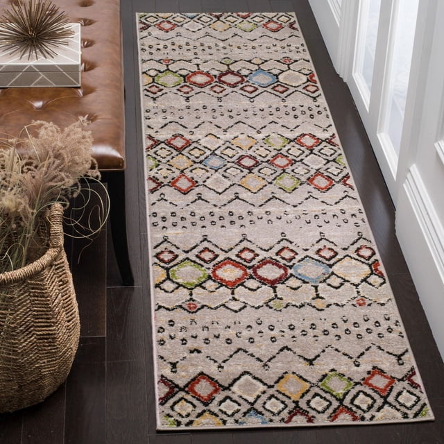 SAFAVIEH Amsterdam Gladwin Geometric Area Rug runner with a beige background and multicolored tribal diamond patterns in red, green, blue, and yellow, power-loomed from durable synthetic yarns, placed on dark hardwood floor beside a brown leather bench and woven basket with dried plants, ideal for adding rustic-chic style to narrow hallways or entryways.