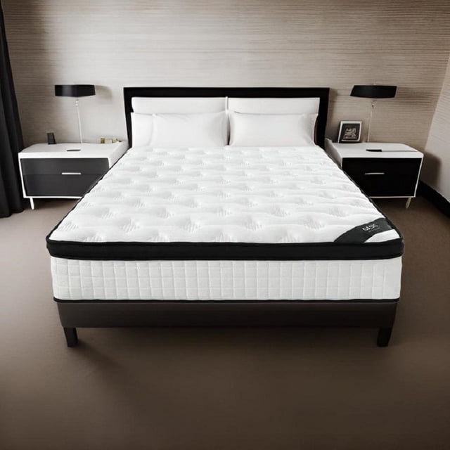 Comfy Bamboo World Rocksteady Oasis Matelas Hybride Ferme de 12 Pouces Format Simple Exposé dans un Cadre de Chambre Moderne. le Matelas Présente un Dessus Matelassé Blanc avec une Bordure Noire, Mettant en Valeur Son design Hybride en Mousse Mémoire à Haute Densité et des Ressorts Durables. Positionné sur un Cadre de Lit Sombre, le Matelas Met en Valeur Son Soutien Ferme et Sa Technologie de Mousse Rafraîchissante pour un Alignement optimal de la Colonne Vertébrale et la Régulation de la Température. Deux tables de Chevet avec Lampes Encadrent le Lit, Soulignant l'Adaptation du Matelas aux Intérieurs Contemporains