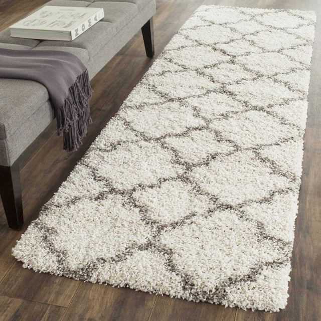 Safavieh Hudson Jaye Tapis Shag Géométrique Ivoire avec Motifs de Carreaux Gris en Forme d'Oignon sur une Épaisse pile Shag Peluche, Posé sur un Plancher de Bois Franc Foncé à Côté d'Un Banc Gris avec un Jeté Violet et un Livre, Idéal pour Ajouter une texture Douce aux Tapis d'Accent dans les Maisons Urbaines Ou Modernes.