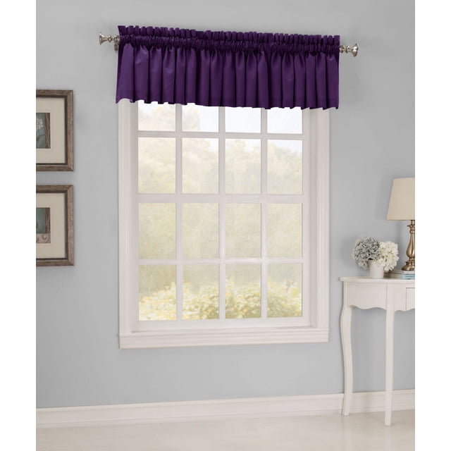 918 HAMPTON MICROFIBER VALANCE in eggplant purple, displayed above a white multi-pane window. The gathered microfiber valance with rod pocket measures 54 inches wide by 17 inches long and softly filters light. It is shown in a room with light gray walls, a white side table with a lamp and floral decor, and framed artwork on the wall. Suitable for adding decorative elegance and subtle light diffusion to window treatments.