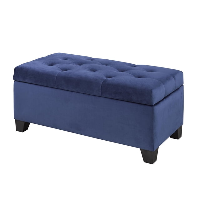 Tufted Storage Ottoman, Navy, with rectangular shape and navy blue fabric upholstery. It has a padded, tufted top with button accents and splayed dark wooden legs. This living room furniture piece provides ample interior storage beneath the hinged top, suitable for extra seating, a tabletop surface, or storing blankets and pillows.
