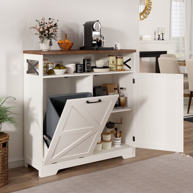 Armoire pour Poubelle Basculante avec Tablette Ajustable pour Poubelle de 10 Gallons, Blanche. Armoire de Style Ferme Conçue pour le Rangement Dissimulé des Déchets, avec Compartiment Basculant, Tablettes Ajustables et Dessus Semi-Ouvert pour un Espace de Rangement Supplémentaire. Fabriquée en Panneau de Fibres de Densité Moyenne durable avec Poignées en Acier Inoxydable, Elle Est Idéale pour les Cuisines, les Salons Ou les Buanderies. l'Image Montre l'Armoire dans un Cadre de Cuisine Moderne et Lumineux avec des Articles de Déco et des Électroménagers sur la surface Supérieure.