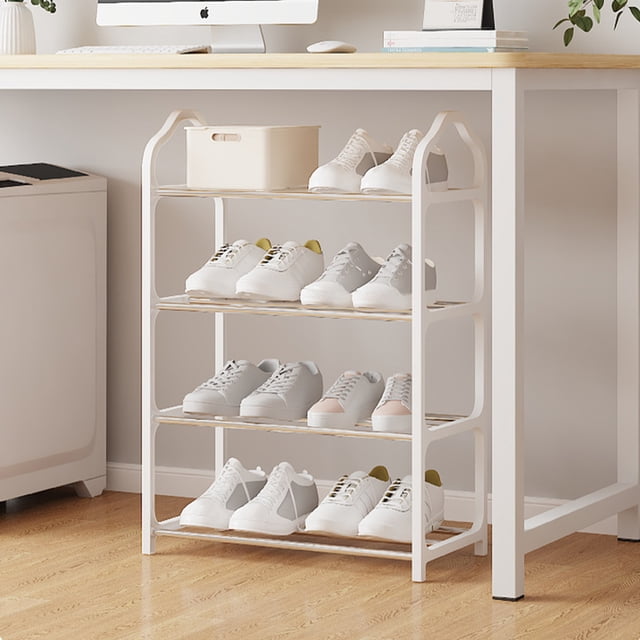 EGNMCR Shoe Rack, a 4-tier shoe rack organizer with metal shelves, shown in a white finish. The rack is placed under a desk in a modern room with wooden flooring, holding multiple pairs of shoes. Designed for use in bedrooms, closets, entryways, or dorm rooms, it features a slatted design for ventilation and drainage. Made of polypropylene and steel tube, it is lightweight yet sturdy, with easy assembly and a compact size of 52x19x4cm.