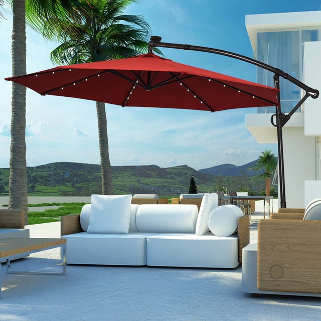 Costway Parasol Déporté de Patio 10 Pi à DEL Solaires, Rotation à 360 Degrés, Bourgogne, Exposé dans un Cadre Extérieur. le Parasol Présente une Auvent en polyester Bourgogne Soutenu par un Poteau en Aluminium Enduit de Poudre et 8 Nervures en Acier. Il Comprend 24 Lumières DEL à Énergie Solaire, avec 3 Lumières sur Chaque Nervures, Offrant un Éclairage la Nuit. le Parasol Offre une Rotation à 360 Degrés et un Ajustement d'Inclinaison pour une Ombrage optimal. un Dessus Ventilé Permet la circulation de l'Air, et une base Croisée Assure la Stabilité