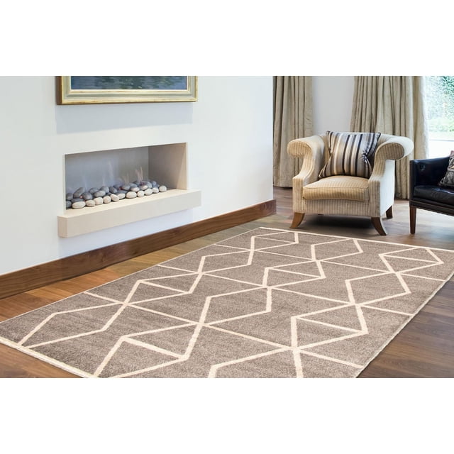ECARPET Tapis de Salon et de Chambre, Tapis d'Intérieur Géométrique Ana Collection avec base taupe et Motif Géométrique en Losanges Crème, Posé sur un Plancher de Bois Franc dans un Salon avec un Fauteuil beige, Coussin à Rayures et Foyer Encastré Moderne avec Pierres Décoratives.