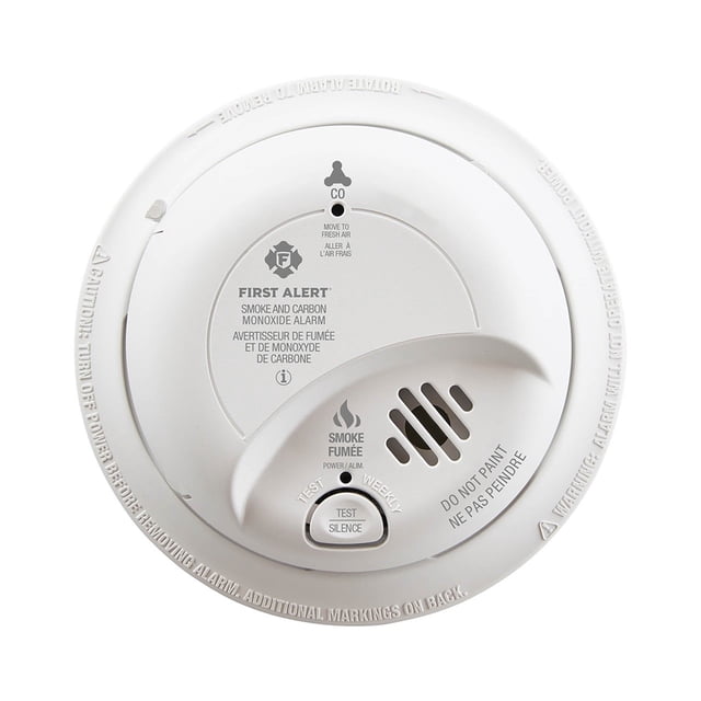 BRK Electronics SC9120BA Hardwired Smoke and CO Alarm with Battery Backup, a round white home safety device with labeled indicators for smoke and carbon monoxide detection. Features a test/silence button, vented grille, and tamper-resistant locking brackets. Designed for hardwired installation with a 9V battery backup for continued operation during power outages.