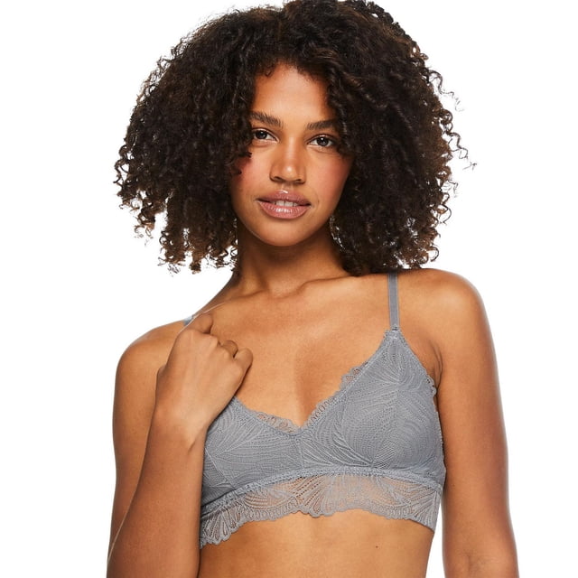 No Boundaries Women's Lace Edge Bra in grey with all-over lace featuring leaf patterns, spaghetti straps, and scalloped lace edges along the bottom band, shown front-facing on a model, suitable for everyday support and layering under various tops.