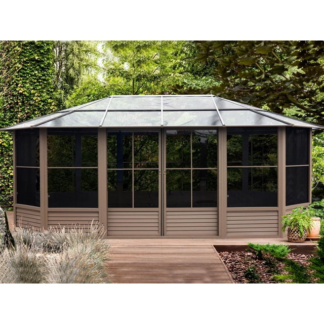 Gazebo Penguin Florence Solarium 12 Pi x 18 Pi dans le Sable Présente un Cadre en Aluminium Enduit de Poudre avec des Panneaux de Toit Renforcés en polycarbonate de 8 mm, des Fenêtres et Portes Coulissantes en PVC avec Moustiquaires Intégrées, Installé sur une Terrasse en Bois Entourée de Verdure de Jardin, Aussi Idéal comme Abri de spa.