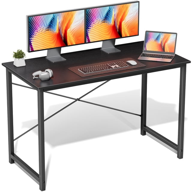 edx 47 inch Small Computer Writing Desk, a durable and modern black desk with a sturdy metal frame and waterproof particleboard surface. The desk is displayed with dual monitors, a laptop, keyboard, mouse, headphones, and a small plant, emphasizing its spacious design for work, studying, or gaming.