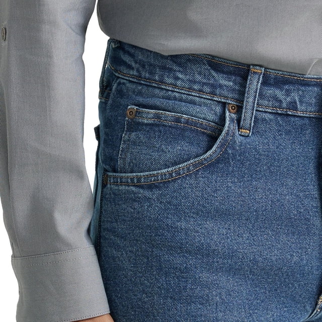 Wrangler Men's Five Star Regular Fit jeans in blue stretch denim with regular fit and straight leg, featuring classic five-pocket design, rivets, scoop front pockets, and waistband patch, shown in close-up side view with grey shirt sleeve, ideal for casual and active wear.