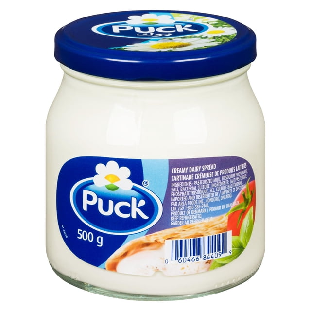 Puck Creamy Dairy Spread in a 500 g glass jar with a blue lid, featuring a white flower logo and label showing bread with spread and tomato, highlighting its smooth, creamy texture ideal for spreading and suitable for cooking or baking.