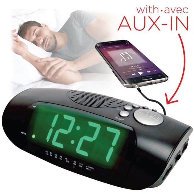 Escape RA930 Réveil Numérique AM/FM à Affichage Jumbo avec AUX Noir, Doté d'Un Écran LED Vert de 1,2 Po. l'Horloge Comprend une radio AM/FM, une Fonction d'Entrée AUX pour Jouer de la Musique à Partir de Téléphones Intelligents Ou de Tablettes, et un Variateur pour le Contrôle de la Luminosité. Elle Offre un Bouton Répétition de 9 Minutes, une Minuterie de Sommeil pour s'Endormir sur la Musique, et l'Option de Se Réveiller avec un Sonore Ou de la Musique. l'Image Montre l'Horloge Connectée à un Téléphone Intelligent