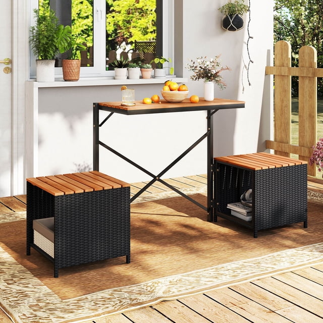 Costway 2-in-1 Outdoor Convertible Bench with Metal Frame PE Rattan Table and Chairs Set shown in a patio setting. The set features a natural acacia wood tabletop and chair seats, complemented by black PE rattan sides. The table and chairs can convert into a loveseat, offering versatility for outdoor use. Built-in storage compartments are visible under the chairs, ideal for holding books or other items. The sturdy metal frame and X-shaped braces enhance stability. The set is placed on a wooden deck with decorative plants and a fence in the background.