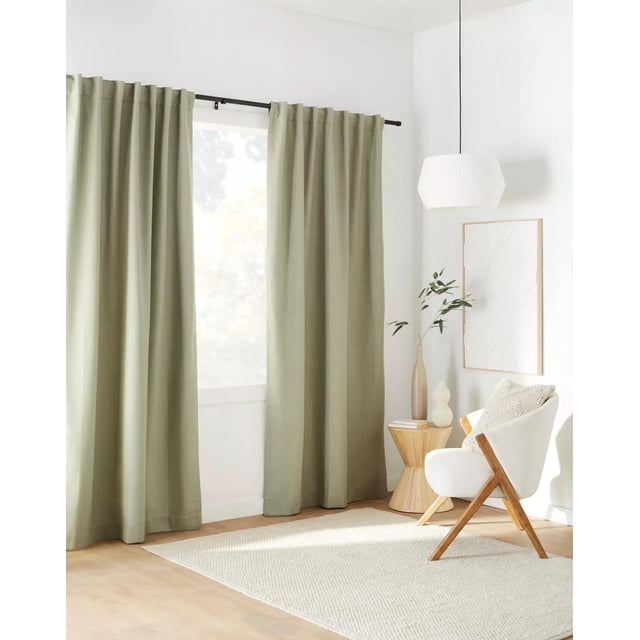 Bouclair Rideau Occultant à Poche pour Tringle et Pattes Arrière Taha Sauge Mesurant 54x84 Pouces (137x213 cm). le Rideau Est Exposé dans un Décor de Salon Moderne, Suspendu à une Tringle Noire, avec Son Tissu Vert Sauge Offrant un Ton Doux et Naturel. la Conception Occultante Assure une filtration de la Lumière, le Rendant Idéal pour Créer une Atmosphère Confortable et Écoénergétique. un Panneau par Paquet, Vendu Séparément.