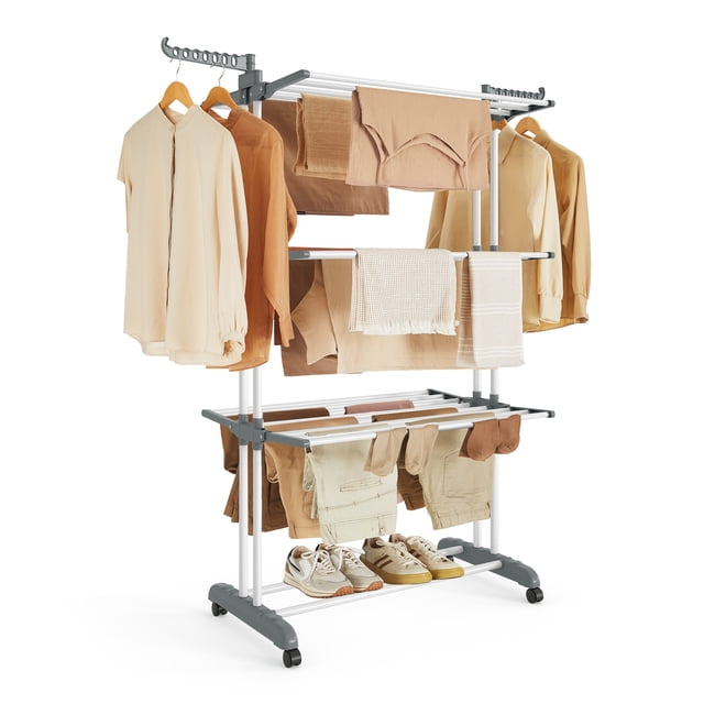 SONGMICS Clothes Drying Rack Stand 4-Tier, a foldable laundry drying rack made of stainless steel and plastic, shown in white. The rack features three top tiers, two rotating wings with 14 slots, and a bottom tier for shoes. It is loaded with various clothing items, including shirts, towels, and pants, as well as shoes on the bottom tier. The rack is equipped with four casters for mobility, with two brakes for stability. Suitable for indoor and outdoor use, it measures 25.2 inches deep, 49.6 inches wide, and 67.7 inches tall when unfolded.