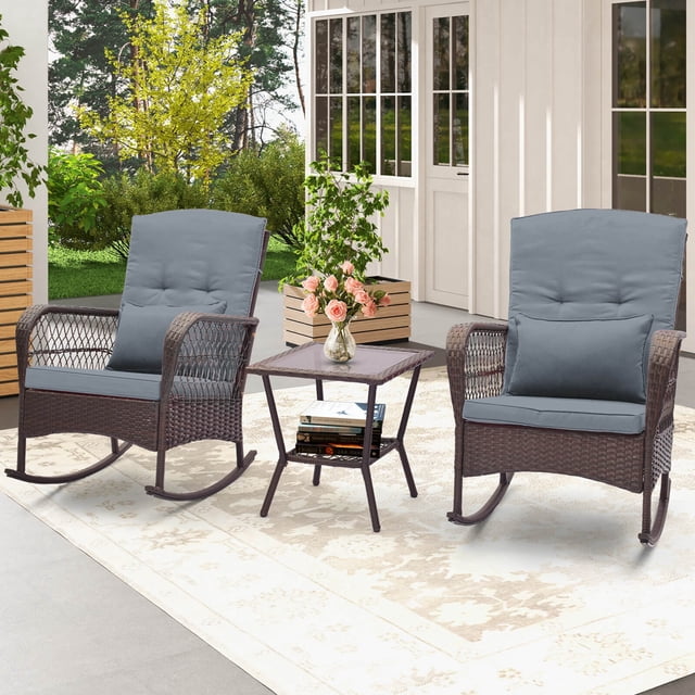 Costway 3 PCS Patio Rocker Set Outdoor Wicker Rocking Chairs with Double-Layer Coffee Table in gray. The set includes two mix brown PE rattan rocking chairs with gray cushions and lumbar pillows, and a double-tier coffee table with a tempered glass top. The chairs feature curved armrests, non-slip rubber mats, and stoppers for safe rocking. The table provides additional storage space with its lower tier. Ideal for patios, gardens, or balconies, this set combines comfort and elegance.