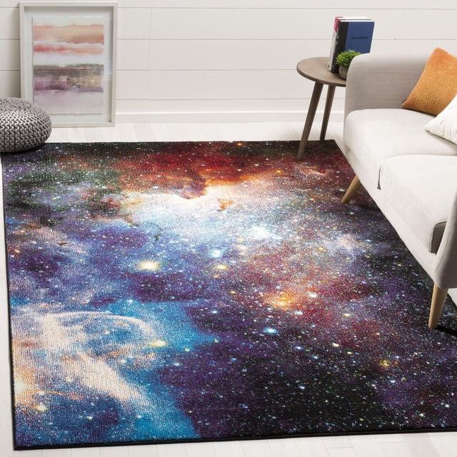 Safavieh Galaxy Kalden Astronomy Area Rug with a celestial galaxy pattern in vibrant blues, purples, reds, and star-like highlights, finely woven for durability and easy care, displayed in a modern living room with light wood flooring, a beige sofa with orange and white cushions, a round wooden side table with books and a small plant, and a framed abstract artwork against a white shiplap wall. This durable accent rug is also ideal for adding a cosmic touch to home offices or reading areas.