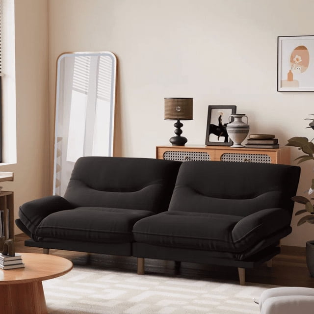 Homall Futon Sofa Bed with Adjustable Backrest & Five Angles Adjustable Armrests, displayed in a contemporary living room. The sofa is upholstered in black fabric with memory foam cushions for superior comfort. Its 65-inch compact design is perfect for small spaces, offering three adjustable positions: upright at 105°, reclined at 160°, and fully flat at 180°. The armrests adjust to five angles for added versatility. The sofa is supported by sturdy wooden legs and complements the room's decor, including a wooden console table, a mirror, and decorative accents.