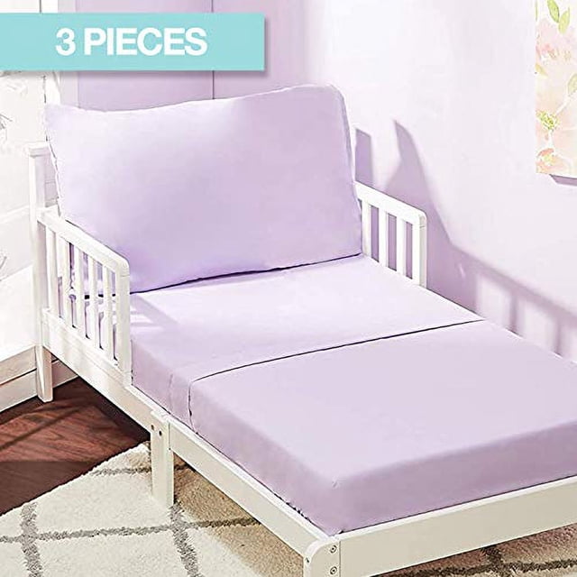 EVERYDAY KIDS 3 Piece Toddler Sheet Set in solid purple, featuring a flat sheet, a fitted sheet, and a pillowcase made of soft, breathable microfiber. The fitted sheet fits standard toddler mattresses (52” by 28”) with an 8” pocket. Displayed on a white toddler bed in a pastel-themed room.