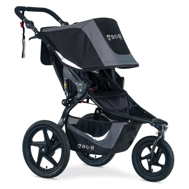 BOB Gear Revolution Flex 3.0 Jogging Stroller in graphite black with three large air-filled tires and suspension system for smooth rides on various terrains, adjustable 9-position handlebar, extra-large cargo basket with mesh sides, and canopy featuring the BOB logo.