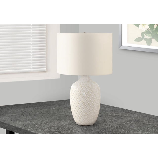 Monarch Specialties Lighting 25"h table lamp with a cream glazed ceramic ginger jar base featuring a diamond geometric texture and an ivory linen drum shade, placed on a dark grey stone end table near a window with white blinds and a framed floral print on a light grey wall, often used to add warm ambient lighting in living rooms or bedrooms.