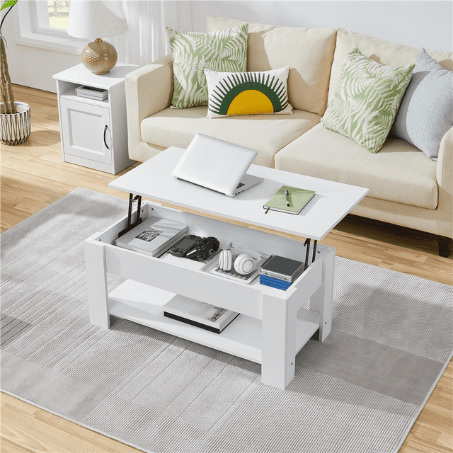Yaheetech Table Basse Moderne à Plateau Relevable en Blanc avec Compartiment Caché et Tablette Ouverte pour Rangement, Placée dans un Décor de Salon. le design à Plateau Relevable Est Montré Étendu, Révélant des Articles Organisés comme des Livres, des Appareils Électroniques et des Écouteurs à l'Intérieur du Compartiment. la Table Est Faite de CARB P2 MDF Résistant à la Chaleur et à l'Eau et s'Asseoit sur un Tapis Gris Près d'Un sofa beige avec des Coussins d'Accent Verts et Jaunes.