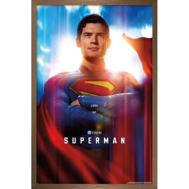 DC Studios Superman (2025) - Affiche Murale Gros Plan d'Une Feuille Montrant une Vue Centrée et Orientée vers l'Avant de Superman en Complet Texturé Bleu avec l'Emblème « s » Rouge et Jaune sur Sa Poitrine, les Bras Croisés, et une cape Rouge Fluide sur un Fond Lumineux Bleu et Blanc Vif, Encadrée en Bois, Convient à la Déco Maison et à l'Art Mural.