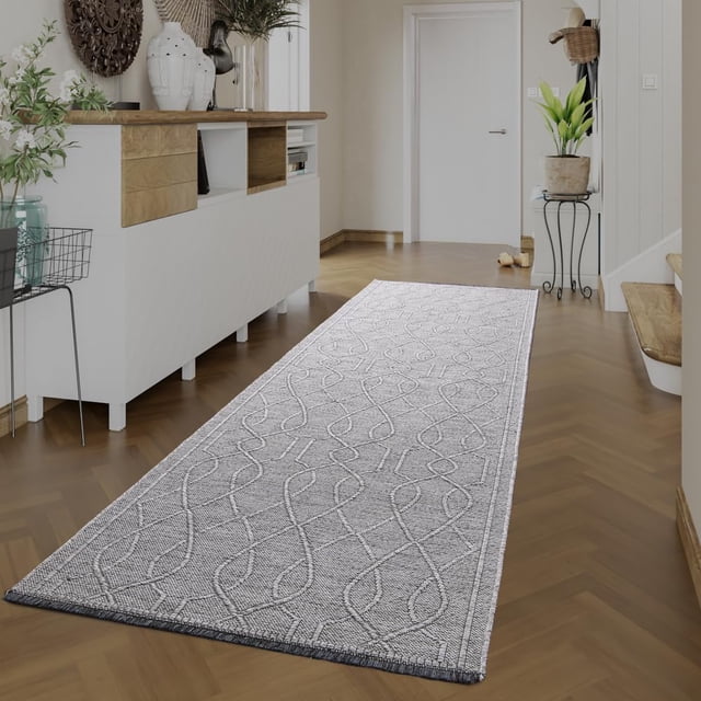 BY COCOON 2'x10' runner rug displayed in a hallway setting with a light grey pattern on a low-pile surface. Made in Turkey with durable cotton and chenille materials, this washable rug is resistant to stains, fading, and shedding. Its non-slip backing ensures stability, making it ideal for high-traffic areas like entryways, kitchens, and hallways. The rug measures 60 cm x 305 cm and features a functional, stylish design suitable for protecting delicate flooring.