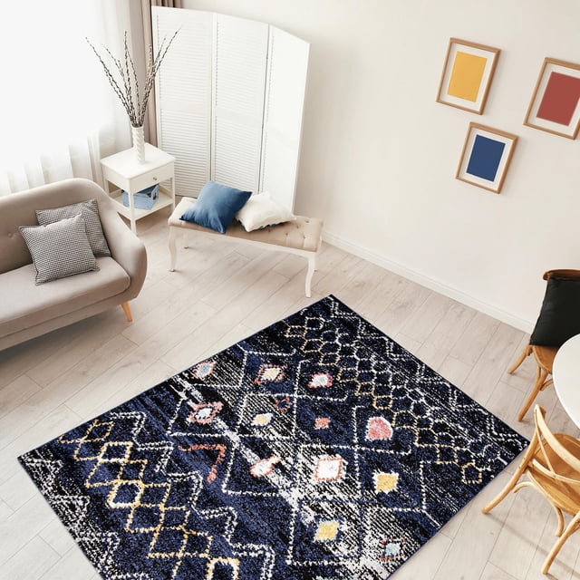 ECARPET Morrocan Area Rug Boho Chic Carpet for Living Room Bedroom, Classic Collection, displayed on light wood flooring with dark blue trellis geometric patterns accented in white, yellow, and pink. Made of soft, durable polypropylene, this stain-resistant rug suits high-traffic indoor spaces. The room features a beige sofa with patterned cushions, a white side table with a vase, a tufted bench with blue and white pillows, and framed abstract art on the wall.