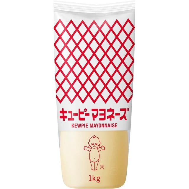 Kewpie Japanese Mayonnaise in a 1kg (2.2lbs) soft squeeze bottle with a red diamond pattern on the white upper section and a beige lower section. The bottle features red Japanese text, 'Kewpie Mayonnaise,' and a baby mascot illustration. Designed for easy dispensing with a narrow tip, this mayonnaise is known for its creamy texture, slightly sweet taste, and umami flavor, ideal for sushi, sandwiches, salads, and dipping sauces.