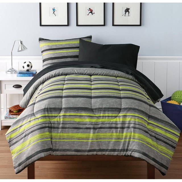 Mainstays Kids Ensemble de Literie Bed-in-a-Bag à Rayures pour Lit Simple avec une Couette et une Taie d'Oreiller à Rayures Horizontales Grises, Noires et Vert lime, Assorti à une Taie d'Oreiller Noire Unie. Fait de 100 % polyester et Lavable à la machine. Montré dans une Chambre d'Enfant avec des Murs Bleu Pâle, des Bois Blancs, une Table de Nuit Blanche avec une Lampe Argentée, des Livres et un Ballon de soccer, et des Imprimés Sportifs Encadrés au-Dessus du Lit.